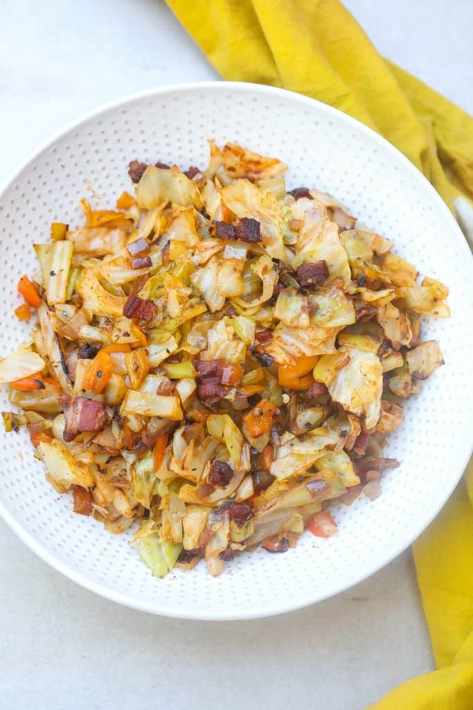 Fried cabbage and bacon on a white plate