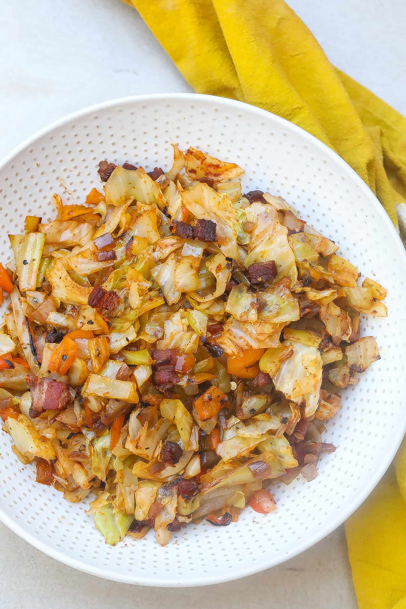 Fried cabbage and bacon on a white plate