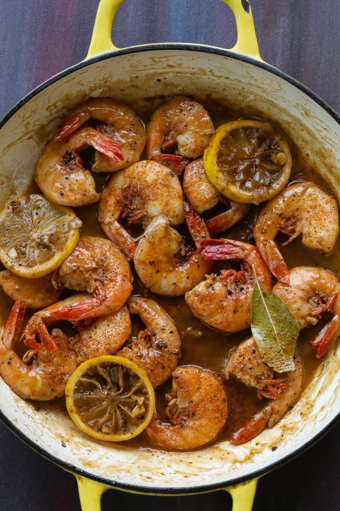 shrimp cooking in a pan with lemons