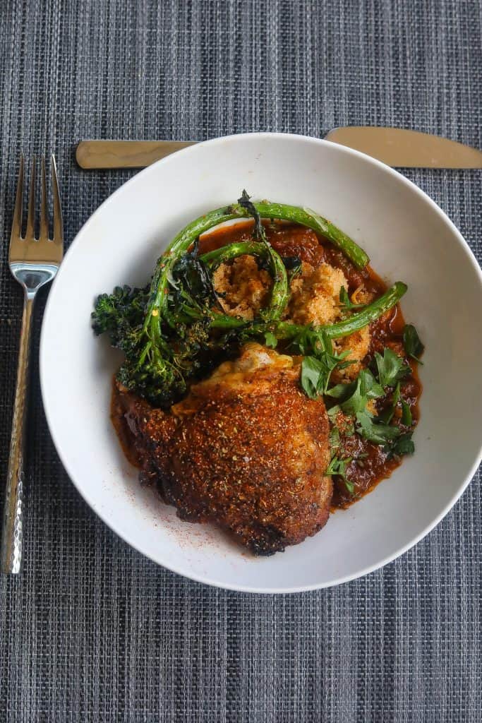 crispy chicken thighs with broccoli and fonio grain in white bowl