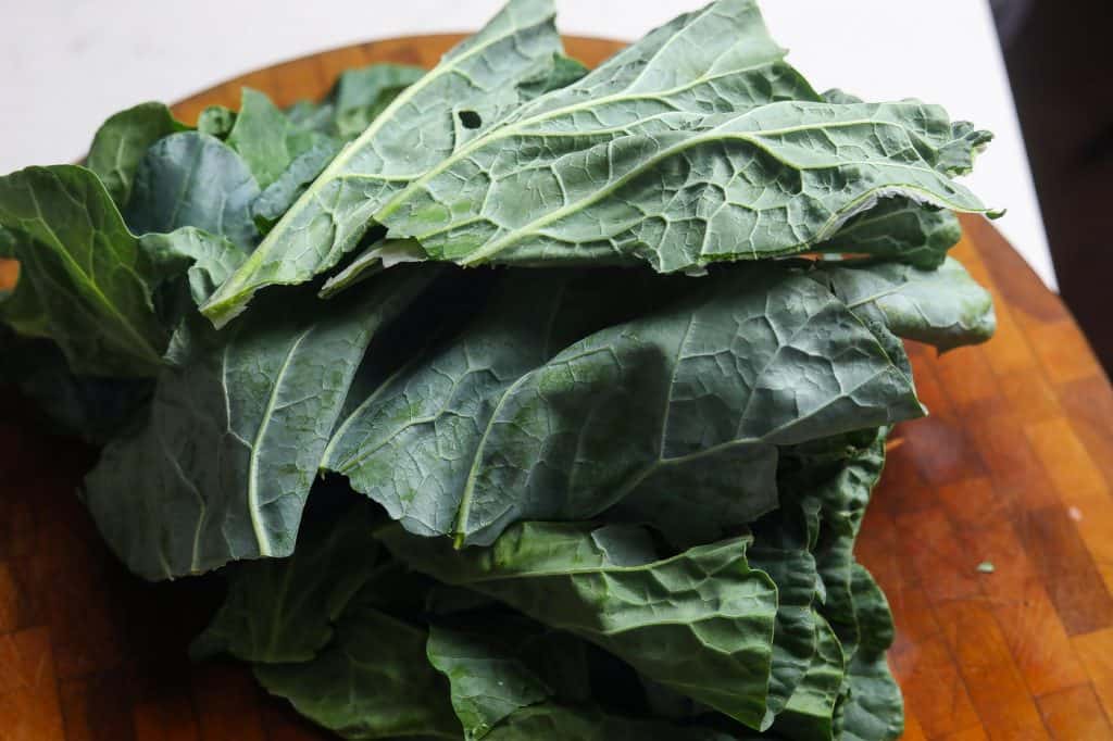 collard leaves stacked on cutting board