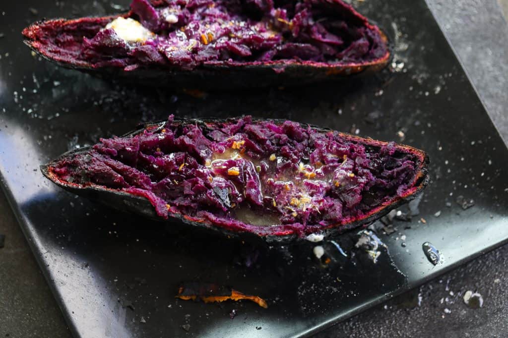 purple sweet potato halves on a black plate