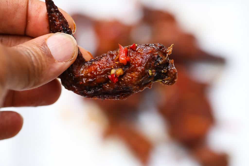 chicken wing held in the air with fingers