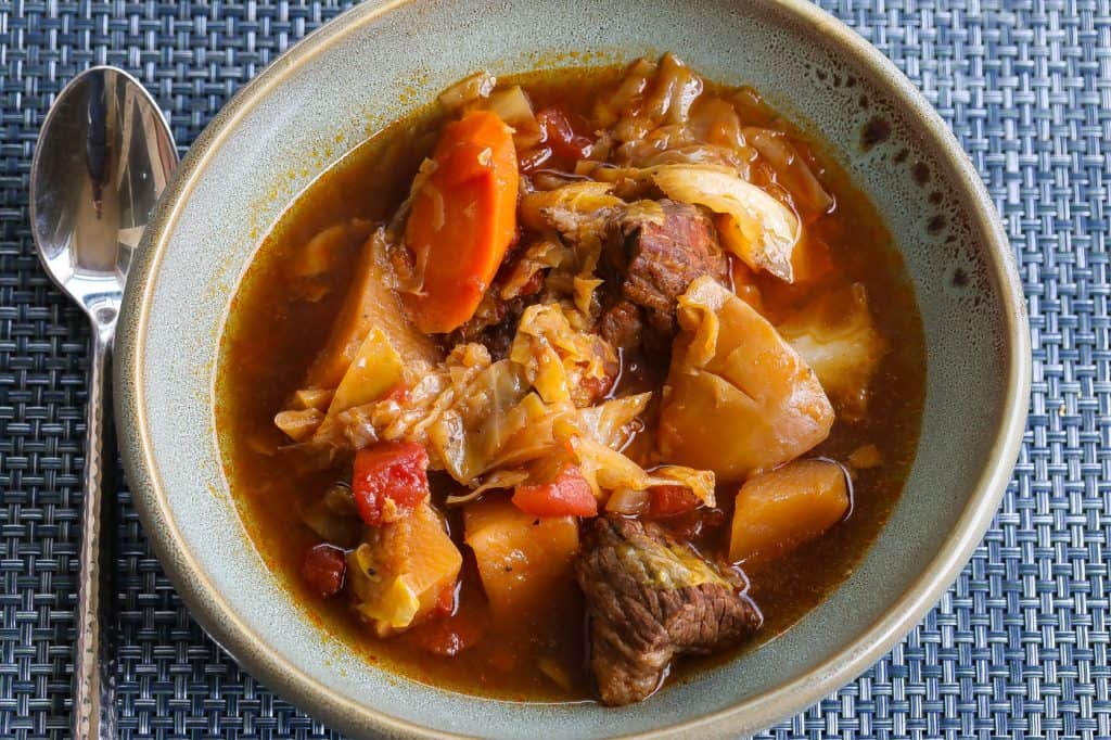 beef and cabbage soup in a large green bowl