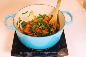 collards and carrots cooking in a blue pot