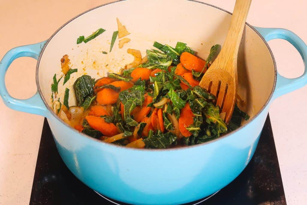 collards and carrots cooking in a blue pot