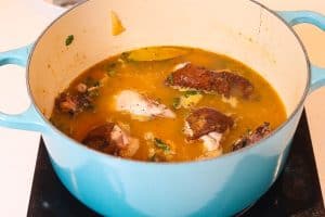 chicken and vegetables cooking in a blue pot