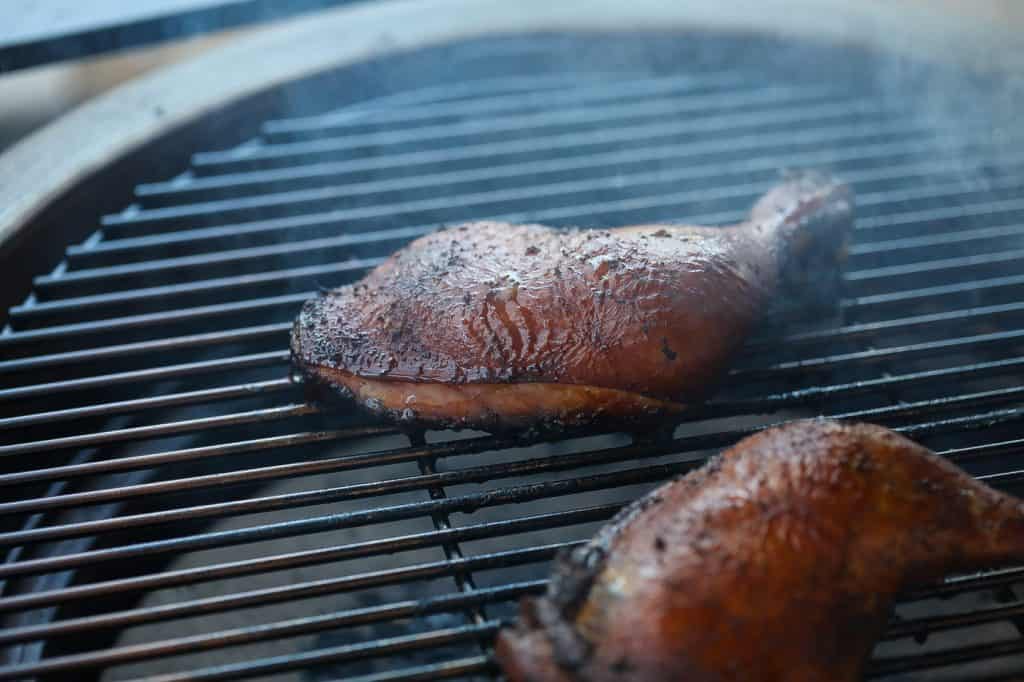 jerk chicken legs smoking on a grill