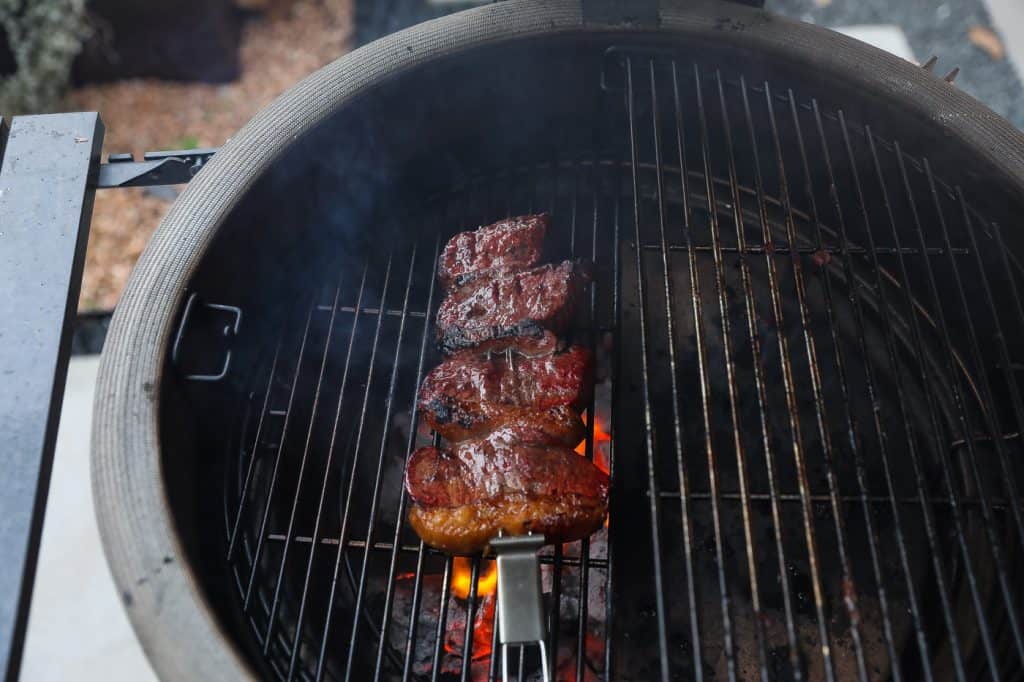 steak grilling over coals