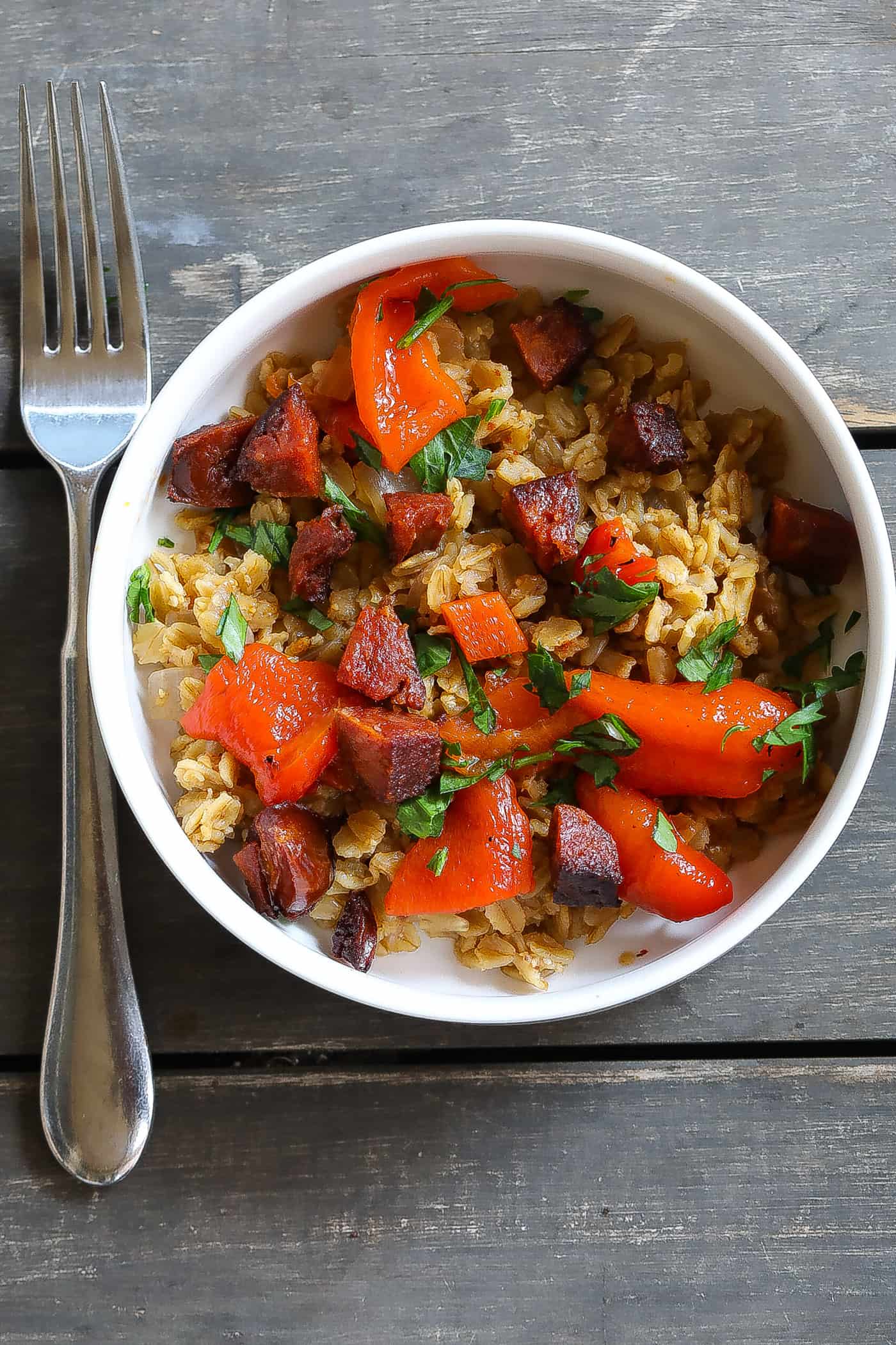 oatmeal with sausage and red peppers in a white bowl