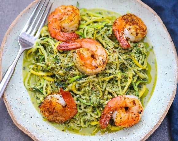 zoodles with pesto topped with shrimp on green plate