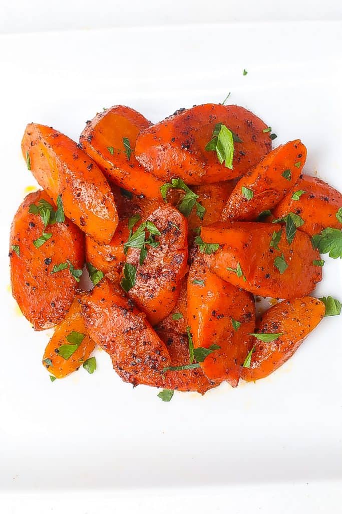 sliced carrots topped with parlsey on a white plate