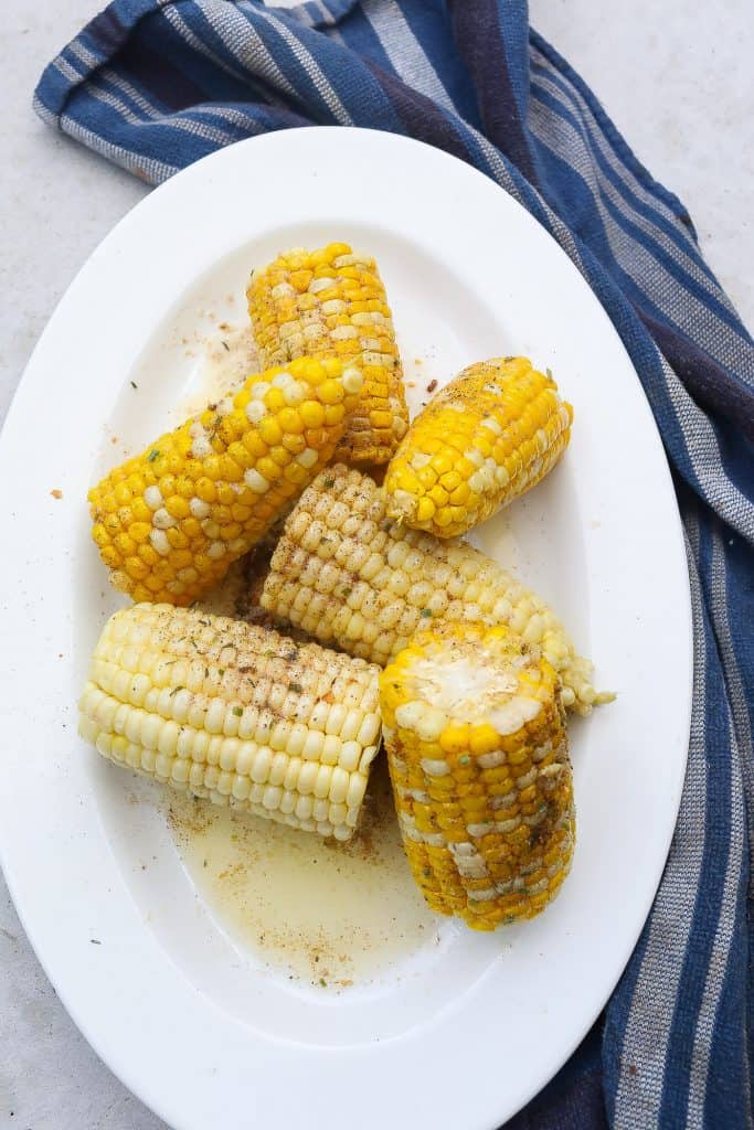 corn on the cob halves on a white oval platter