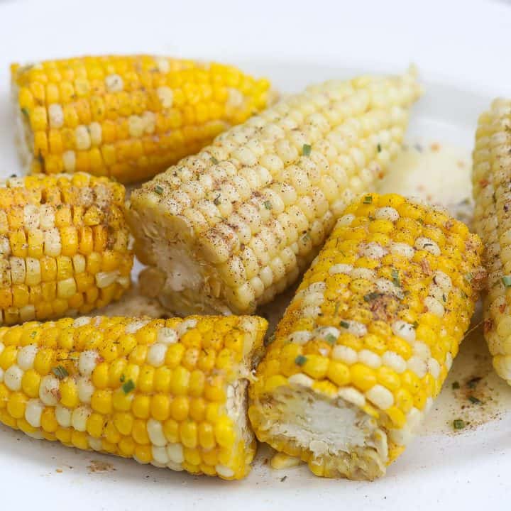 corn on the cob halves on a white oval platter