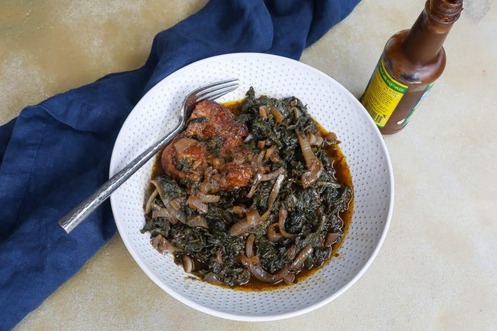 mustard greens with onions and turkey in a white bowl