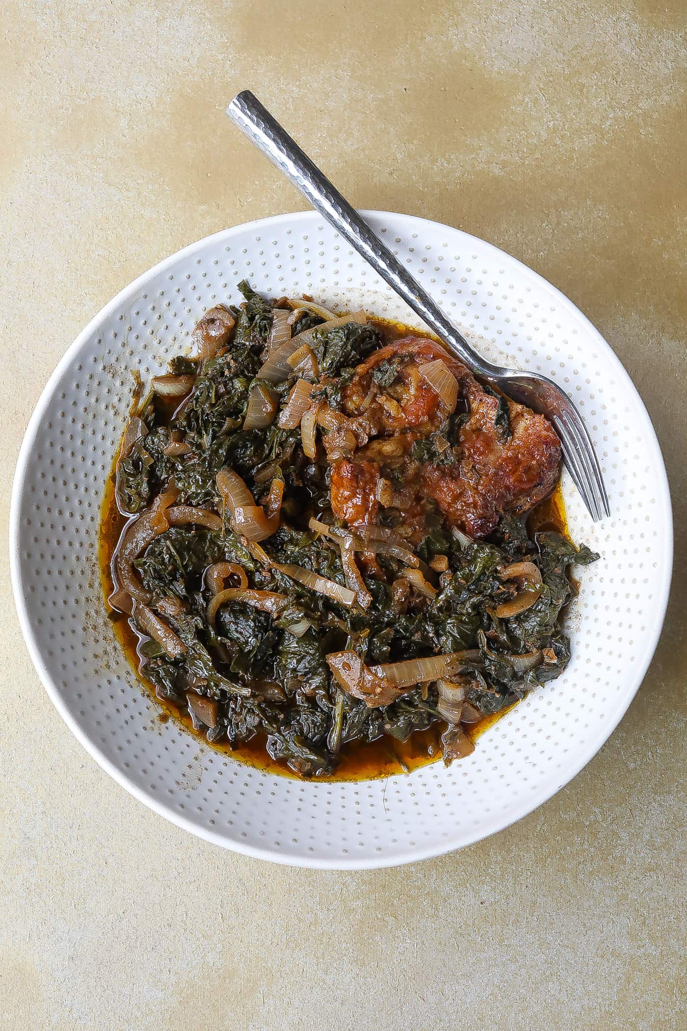 mustard greens with onions and turkey in a white bowl
