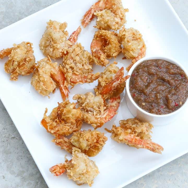 coconut shrimp on white plate with sauce