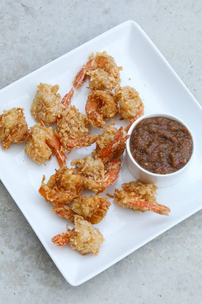 coconut shrimp on white plate with sauce