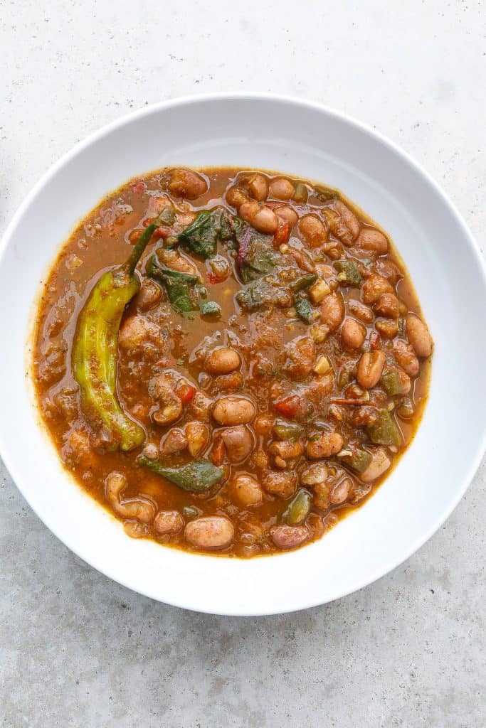 cranberry beans in a white bowl with greens and a pepper