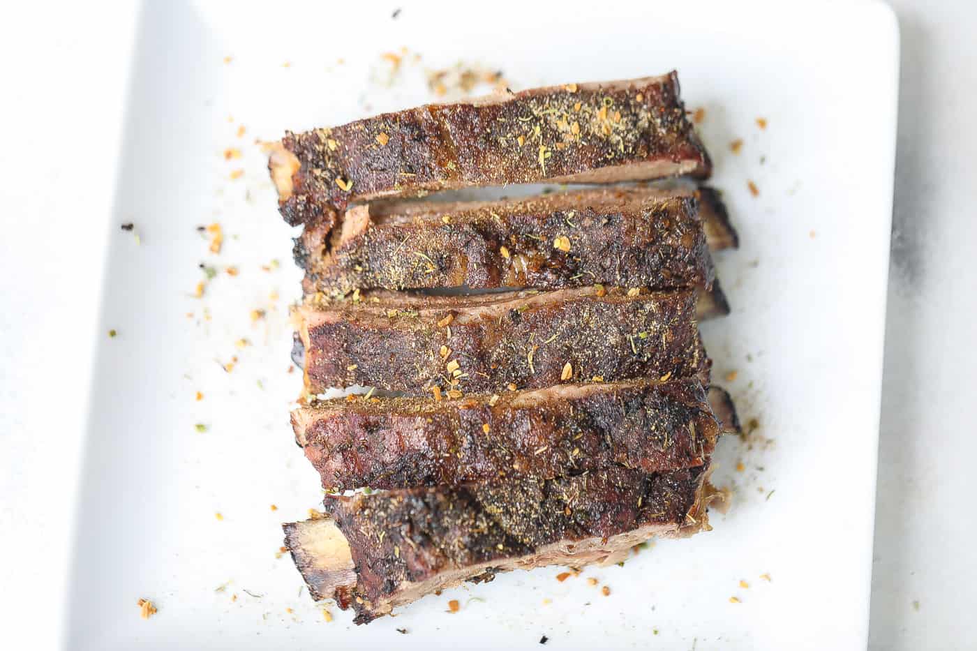 4 ribs on a white plate topped with dry spices