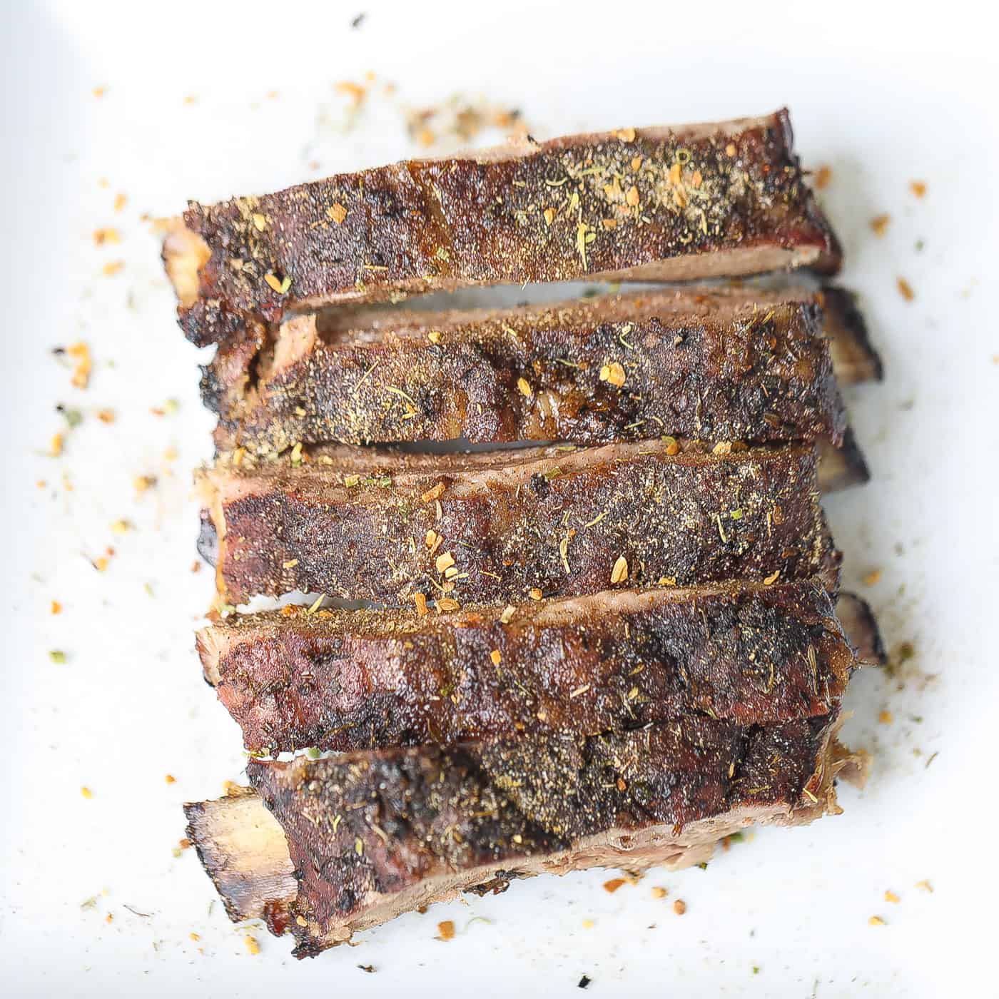 4 ribs on a white plate topped with dry spices