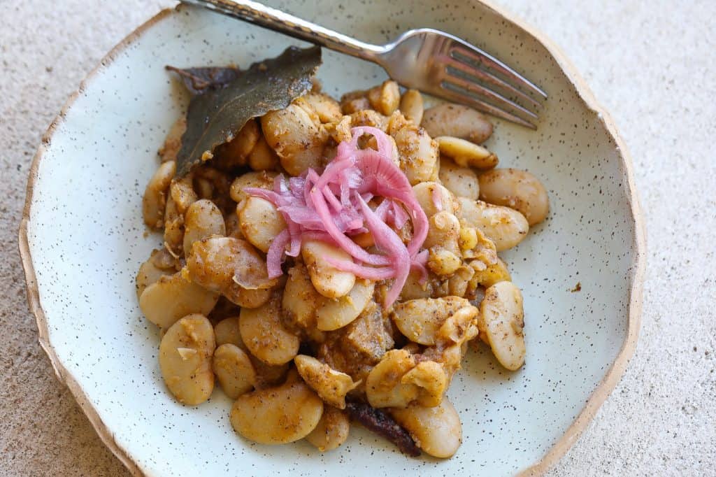 lima beans in green bowl topped with pickled red onions
