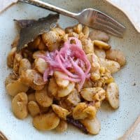 lima beans in green bowl topped with pickled red onions