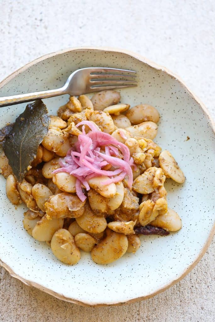 lima beans in green bowl topped with pickled red onions