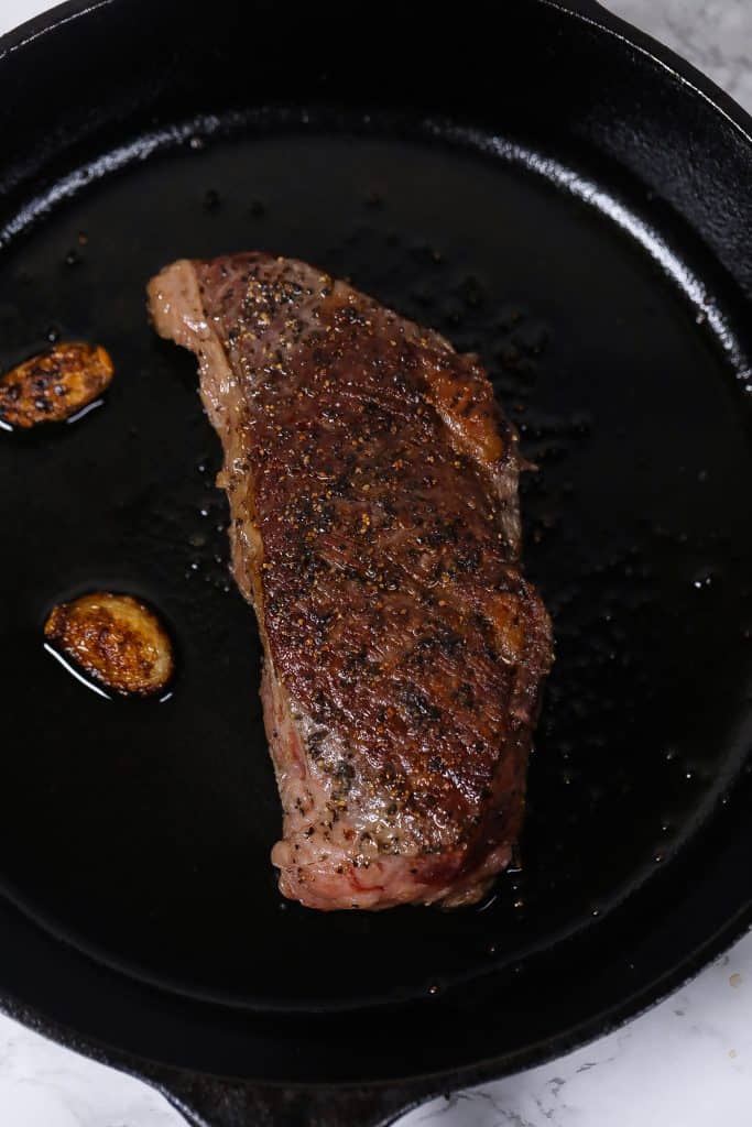 steak in cast-iron skillet with garlic