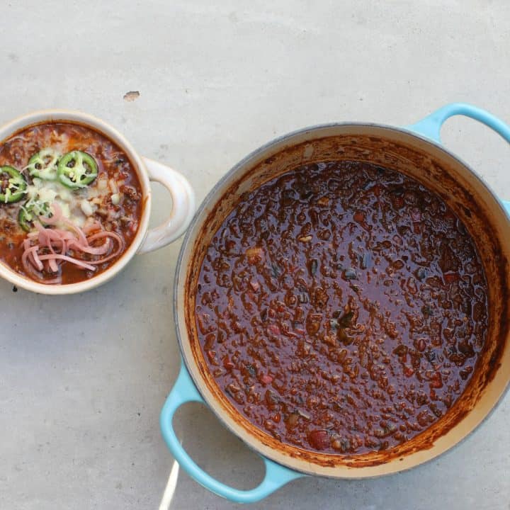 bison chili in white bowl topped with onions, jalapenos, and red onions