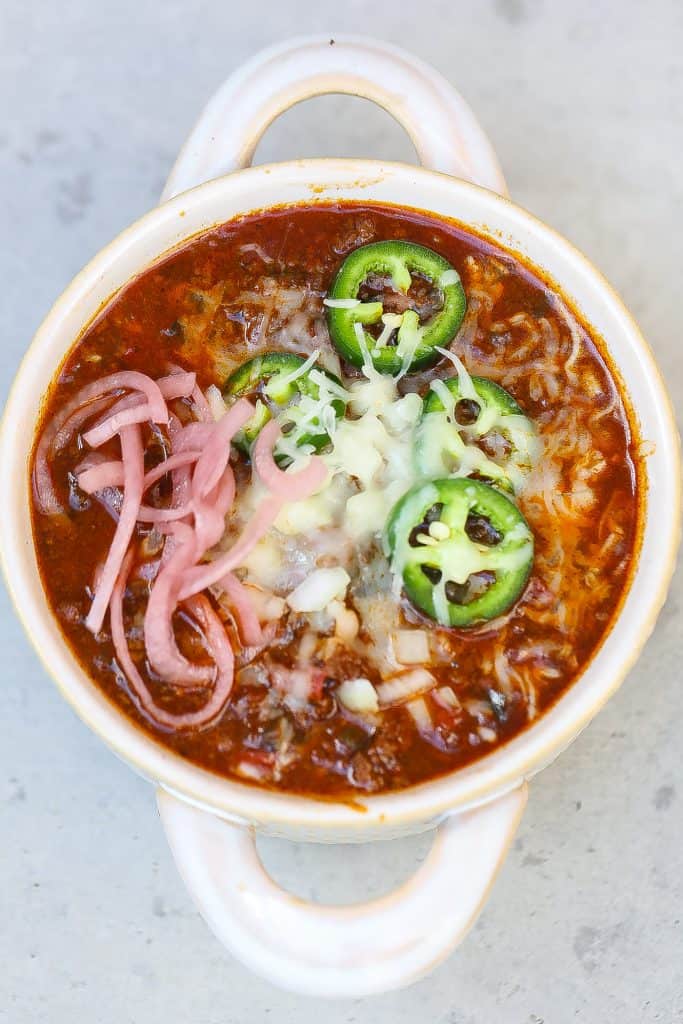 bison chili in white bowl topped with onions, jalapenos, and red onions