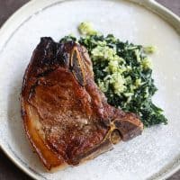 pork chop on top of spinach on tan plate