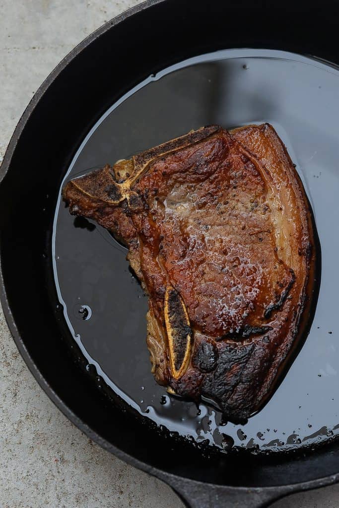 cooked pork chop in black skillet