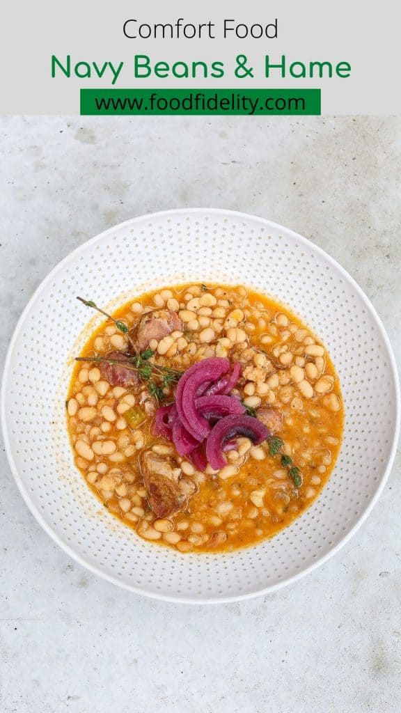 navy beans and ham in a white bowl topped with red onions