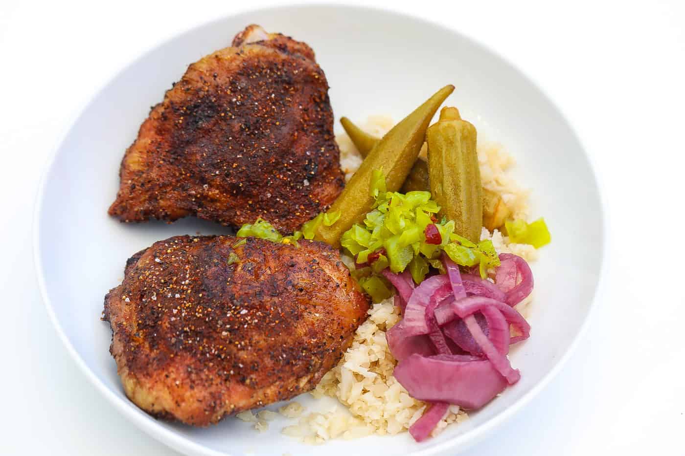 smoked chicken thighs in a white bowl with onions and okra