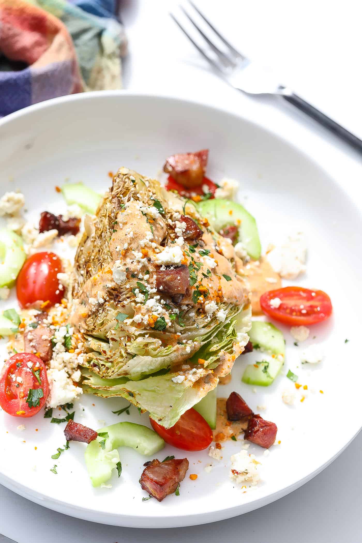 wedge salad on white plate with tomatoes and dressing