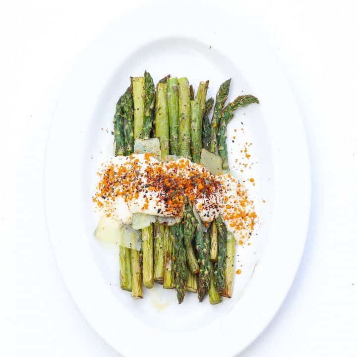 asparagus on a white plate topped with cheese sauce