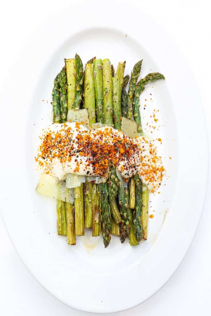 asparagus on a white plate topped with cheese sauce