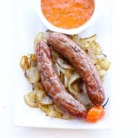 brats on a pile of caramelized onions with sauce