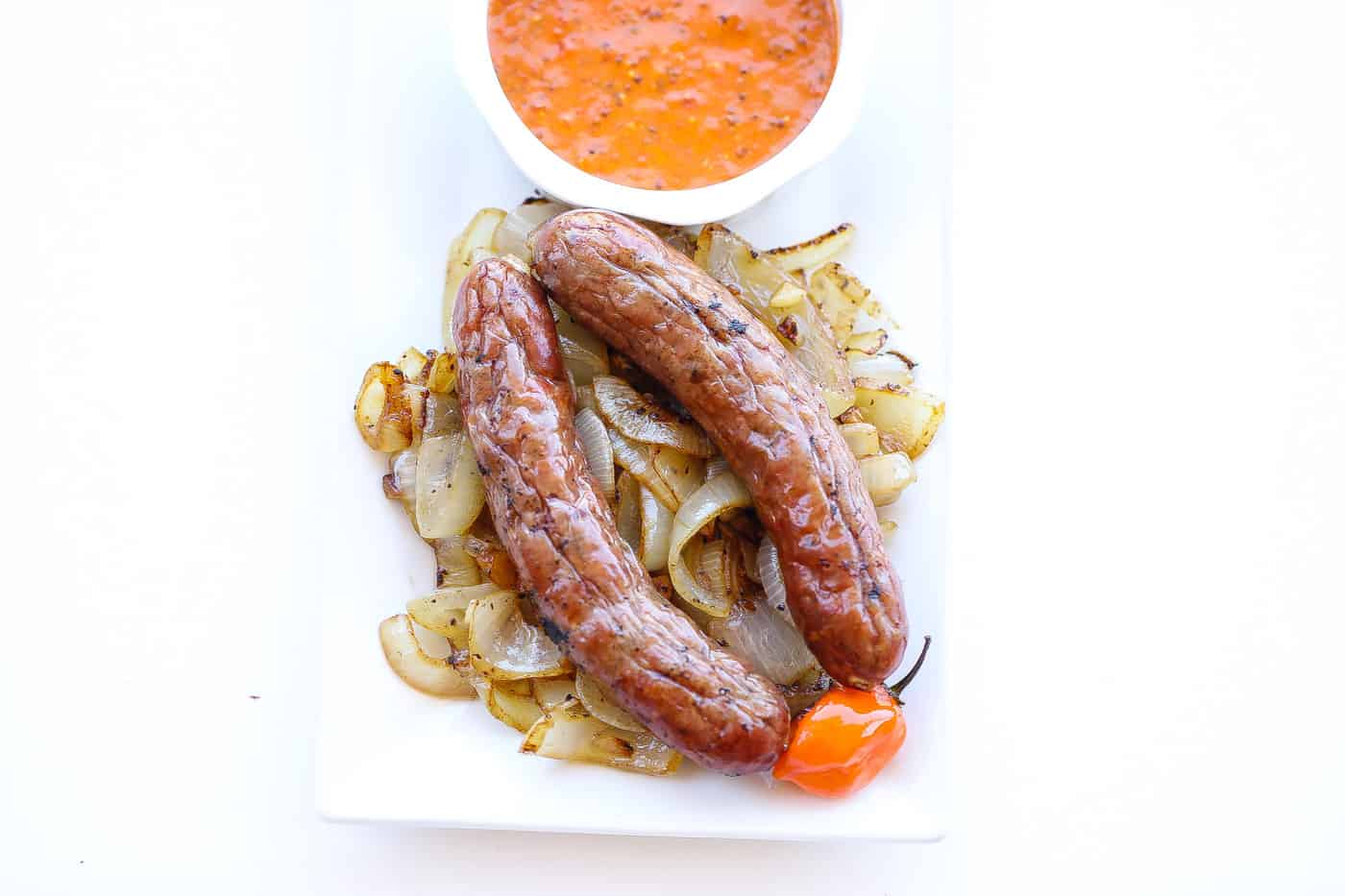 brats on a pile of caramelized onions with sauce