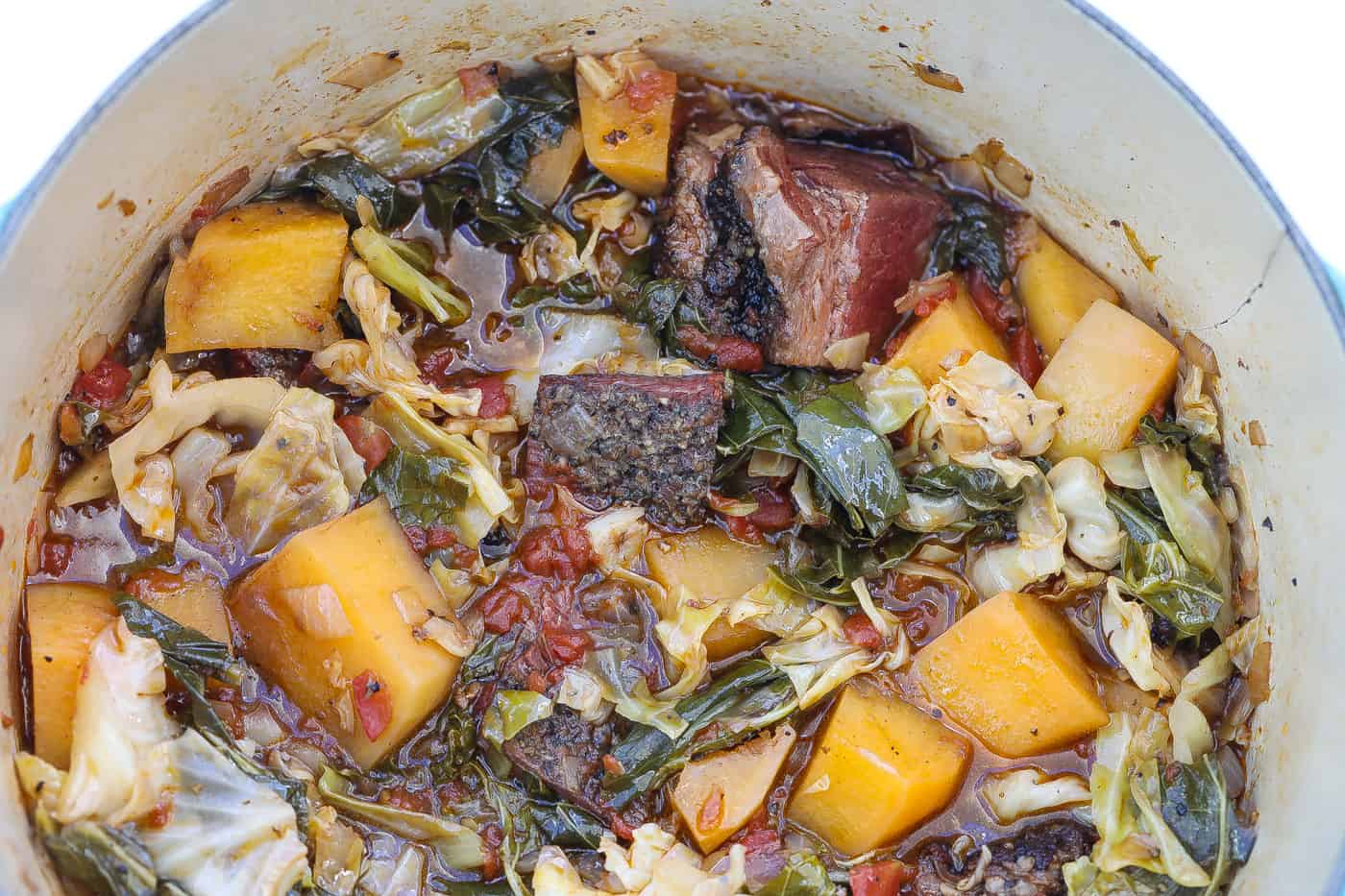 cabbage stew with brisket and rutabagas in blue pot.