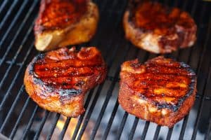 4 pork chops on the grill cooking with fire
