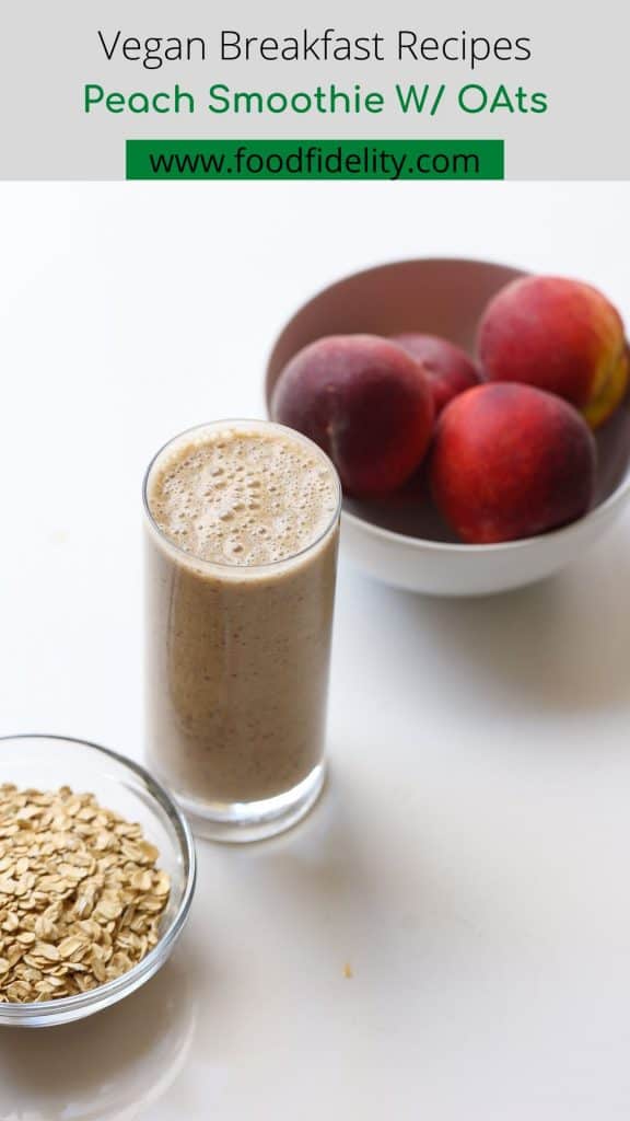 oatmeal smoothie in a tall glass with peaches and oats on the side