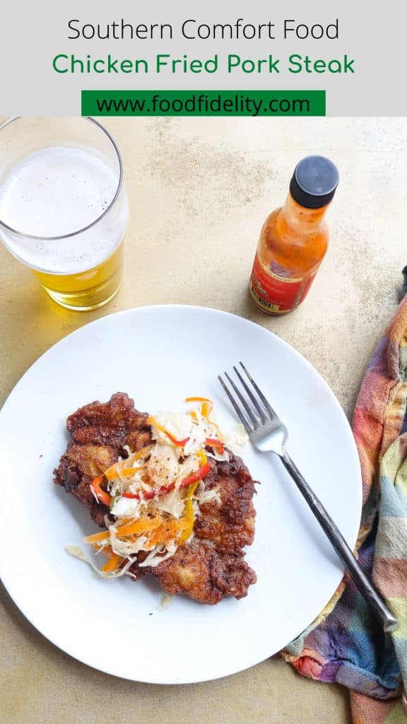 fried pork steak on white plate topped with slaw