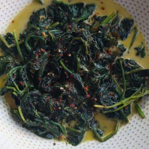 sauteed spinach in a white bowl with creamy sauce