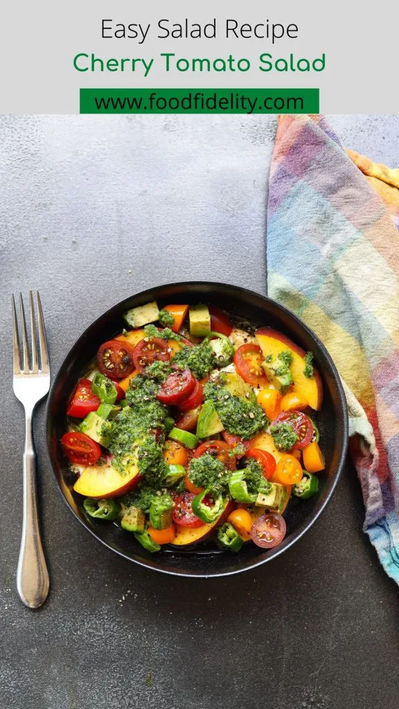 cherry tomato salad topped with green sauce in black bowl