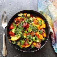 cherry tomato salad topped with green sauce in black bowl