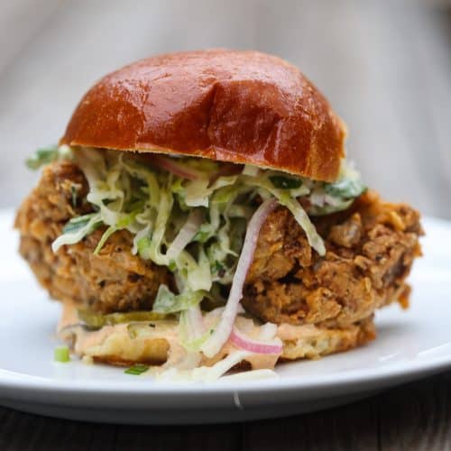vegan fried chicken sandwich with slaw on a white plate