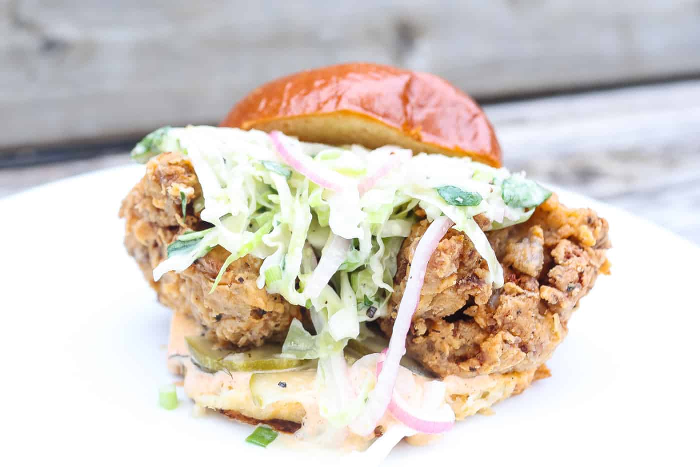 vegan fried chicken sandwich with slaw on a white plate