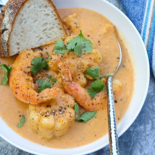 shrimp and corn in a white bowl with bread slice